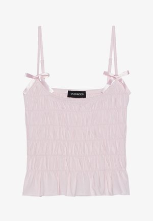 Light pink camisole top with adjustable satin straps and a smocked texture, featuring a ruffled hem and a brand label at the center.
