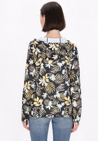 Zwarte hooded jack met een bloemenpatroon in geel en blauw. Heeft lange mouwen en een gestructureerde stof. Casual fit, gezien vanaf de achterkant.