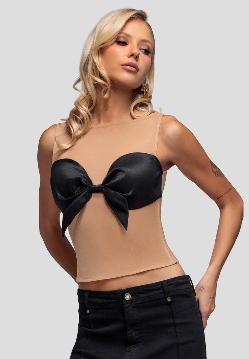 Czarna satynowa bluzka z kokardą na górze, wykonana z beżowej, przezroczystej tkaniny. Charakteryzuje się dopasowanym krojem i regulowanymi ramiączkami, podkreślającymi zarysowaną sylwetkę.