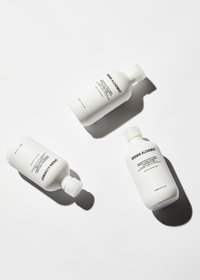 Tre vita plastflaskor märkta "Grown Alchemist" med minimalistisk design och svart text, som visar olika produktnamn och användningsområden.