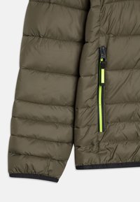 Odjeljak s maslinasto zelenom puffer jaknom, koja ima kvadratni uzorak šivanja, crni zatvarač s svijetlozelenom povlačnom trakom i rukavima s crnim obrubom.