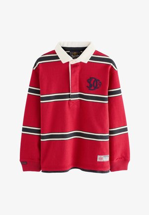 Červené rugbyové tričko s bielymi a námorníckymi vodorovnými pruhmi, bielym golierom a výšivkou loga na ľavej strane hrudníka.