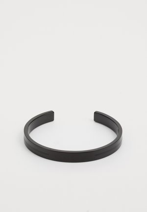 Bracelet en métal noir avec une finition lisse et mate, comportant deux rainures parallèles et un design simple à extrémités ouvertes.