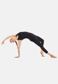 Svart åtsittande linne och leggings. Figuren balanserar på ena handen, böjer sig bakåt och visar upp flexibilitet och styrka.