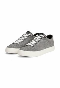 Szare materiałowe sneakersy z białymi podeszwami i sznurowkami, z czarną łatką z logo na języku oraz subtelnymi czerwonymi i niebieskimi akcentami.