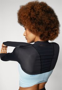 Black long-sleeve top with ribbed texture transitioning to a light blue body. Features a fitted design and ruched back detail.