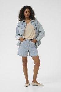 Veste en denim bleu clair avec broderie florale, haut v-neck beige, shorts en denim bleu clair et ballerines beiges. Texture lisse, coupe décontractée.
