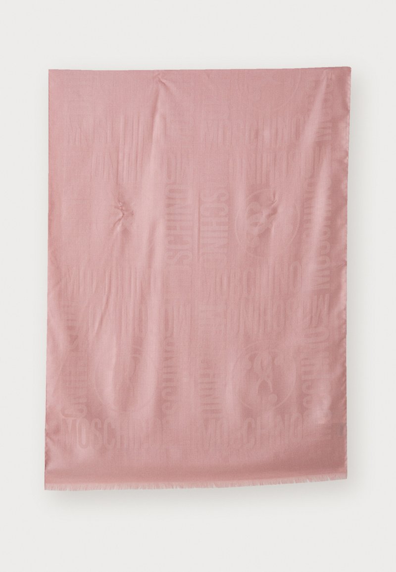 Couverture en tissu rose avec un motif de logo et de texte en relief subtil. Les bords sont à franges et la texture semble lisse et douce.