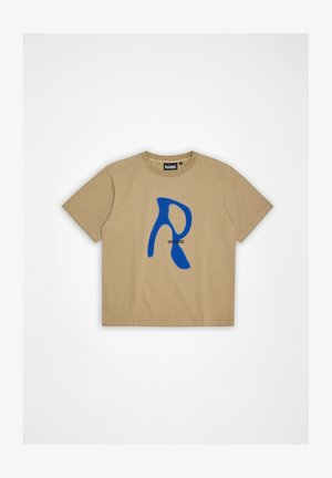 Μπεζ κοντομάνικη μπλούζα με στρογγυλή λαιμόκοψη, διακοσμημένη στο μπροστινό μέρος με ένα μεγάλο μπλε αφηρημένο γράμμα "R" και μικρούς μαύρους αριθμούς.