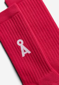 Rippensocken in Rot mit einem weißen Buchstaben "A"-Logo, das an der Seite eingewoben ist, aus einem weichen, strukturierten Stoff für Komfort.
