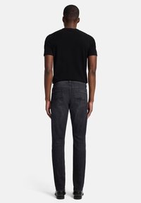 Svart kortärmad skjorta och mörkgr�å raka jeans sedd bakifrån, med två bakfickor och en slät textur.