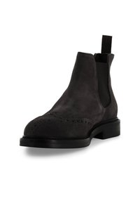 Stivale Chelsea in camoscio nero con punta arrotondata, dettagli decorativi brogue, inserti elastici laterali e suola resistente.