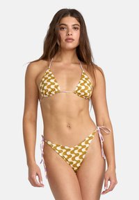 Conjunto de bikini en amarillo con un patrón de olas en blanco. La parte superior presenta copas de triángulo con tirantes finos, y la parte inferior tiene lazos en los costados.