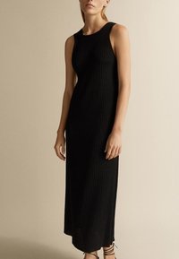Robe midi noire à rayures avec un décolleté arrondi et une silhouette ajustée. Le matériau est lisse et légèrement extensible, mettant en valeur la forme.