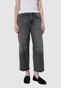 Szerokie dżinsy w wyblakłym szarym denimu, z pięcioma kieszeniami, szlufkami na pasek oraz lekko przetartą fakturą na końcach nogawek.