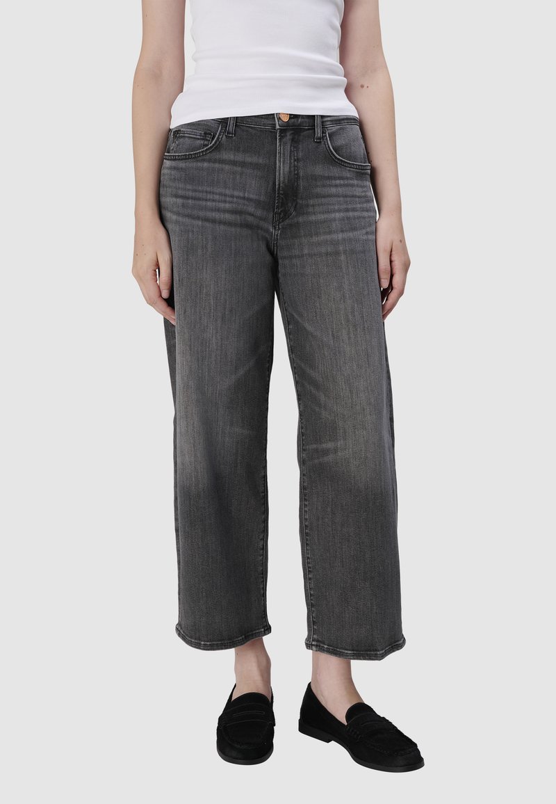 Szerokie dżinsy w wyblakłym szarym denimu, z pięcioma kieszeniami, szlufkami na pasek oraz lekko przetartą fakturą na końcach nogawek.