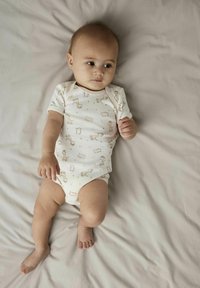 Combi short en coton à manches courtes de couleur écrue avec des motifs d'animaux fantaisistes et des pois. Texture lisse, coupe ajustée et tissu doux.
