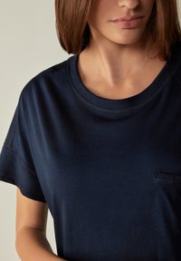 T-shirt blu navy scuro realizzato in tessuto morbido, con scollatura rotonda, maniche corte e una piccola tasca sul lato sinistro.