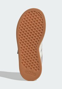 Semelle de chaussure Adidas avec un motif en nid d'abeille, comportant un caoutchouc orange texturé. Inclut un détail du logo ; forme courbée le long du bord.
