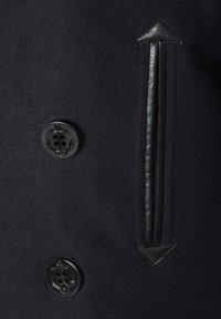 Manteau en laine noire avec un grand bouton en forme d'ancre noire, des accents en cuir, un motif de flèche et une texture lisse.