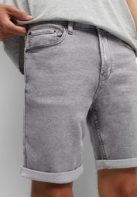 Grijze denim shorts met opgerolde omslagen, met een klassiek vijf-pocket ontwerp en subtiele vervaging. Materiaal is glad met een lichte glans.