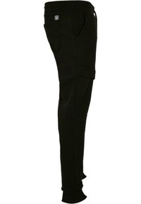 Sorte bomulds joggerbukser med tætsiddende pasform, elastisk talje, sidelommer og en stiklomme på låret. Glat tekstur.