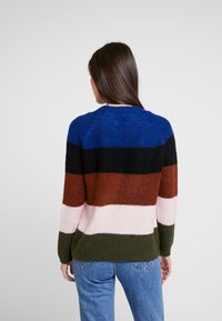 Sweter dziergany z poziomymi paskami w kolorach niebieskim, czarnym, brązowym, różowym i zielonym. Luźny fason z prążkowaną teksturą i okrągłym dekoltem.