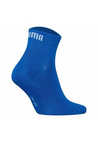 Calcetín azul hasta el tobillo hecho de un material suave. Presenta un puño acanalado con el logotipo blanco de "PUMA". El diseño incluye una puntera y un talón reforzados.