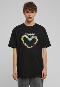 Camiseta negra de algodón con un gráfico de corazón colorido inspirado en dulces con "UPSCALE" arriba, de corte relajado y mangas cortas.