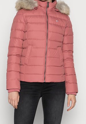 Doudoune rose avec texture matelassée horizontale, capuche en fourrure, fermeture éclair frontale et poches latérales, associée à un jean noir.