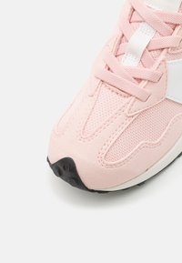 Baskets rose clair avec des matériaux en mesh et en daim, bout rond, accents blancs et semelle noire texturée avec une semelle en caoutchouc.