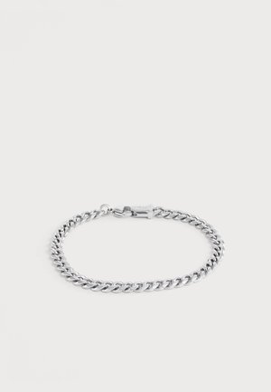 Bracelet chaîne ton argent avec fermoir mousqueton, posé à plat sur un fond clair.
