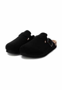Los zuecos de ante negro tienen una puntera cerrada, una textura suave, una correa ajustable, una plantilla de corcho y una suela plana de goma.