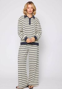 Conjunto de ropa de salón a rayas en crema y azul marino. Presenta una parte superior con cuello y botones, y pantalones de pierna ancha, hechos de una tela suave con un acabado texturizado.