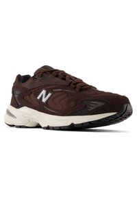 Brown athletic sneakers with a blend of mesh and suede material, featuring a thick cushioned sole and a prominent white logo on the side.
