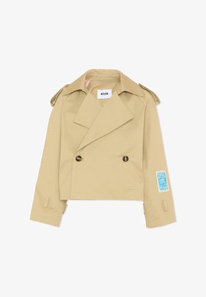 Trench-coat beige court avec larges revers, boutons croisés, pattes d'épaule et un écusson bleu sur la manche droite.