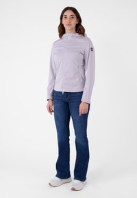 Giacca zip-up lavanda chiaro con cappuccio e tasche laterali. Realizzata in materiale leggero e liscio. Abbinata a jeans blu e sneakers bianche.