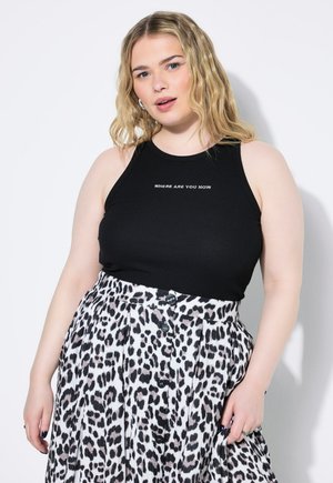 Top in cotone nero a costine con la scritta bianca "DOVE SEI ORA", abbinato a una gonna bianca plissettata con motivo leopardato nero e bottoni.