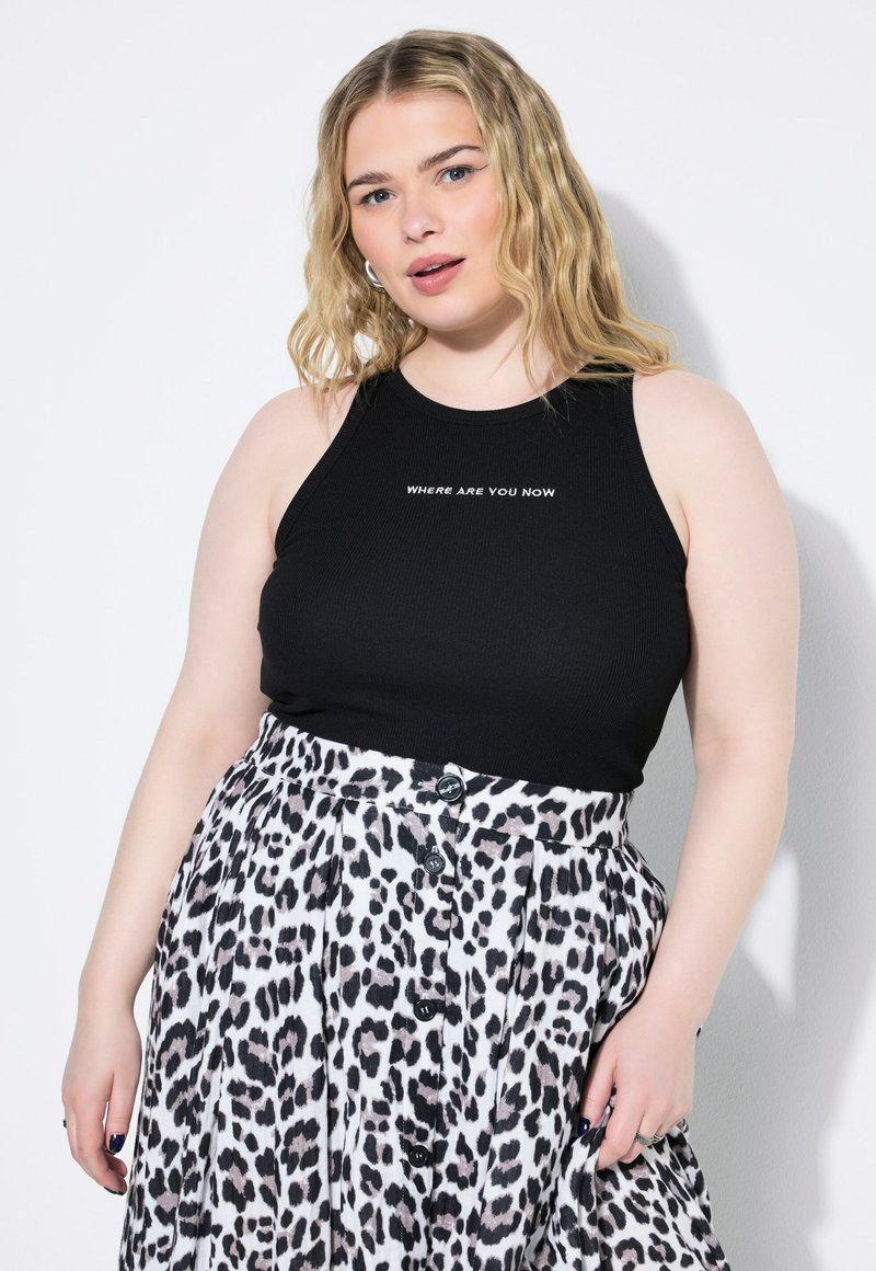 Top in cotone nero a costine con la scritta bianca "DOVE SEI ORA", abbinato a una gonna bianca plissettata con motivo leopardato nero e bottoni.