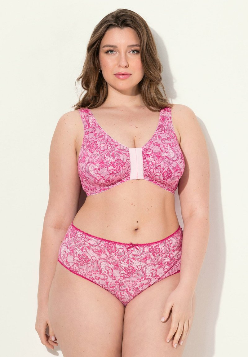 Ensemble de lingerie rose avec motif en dentelle florale, comprenant un bralette avec de larges bretelles et une fermeture à crochets, associé à une culotte taille haute assortie.