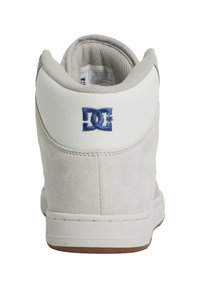 Vysoké tenisky světle šedé nubukové kůže s bílým síťovaným límcem. Obsahují modrou vyšívanou značku a hnědou gumovou podešev.