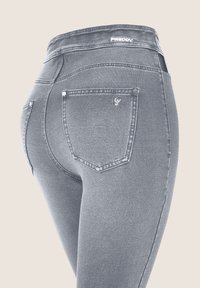 Jeans de mezclilla gris con cintura alta, que cuentan con bolsillos traseros y detalles de costura sutil. Textura suave y diseño ajustado.