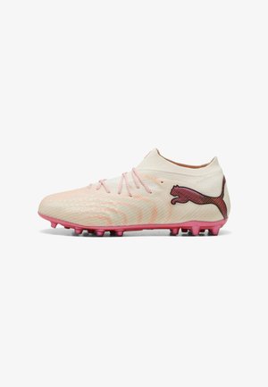 Lyserød fodboldstøvle med tekstureret overflade, lyserøde snørebånd og sort Puma-logo på siden, med formstøbte knopper på ydersiden.