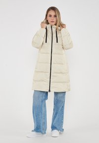 Piumino chiaro con cappuccio, zip nera e coulisse. Presenta un motivo a righe orizzontali; abbinato a jeans a gamba larga blu e sneakers bianche.