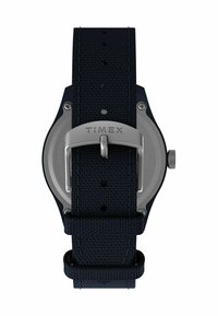 Montre Timex avec un bracelet en textile bleu marine, une boucle en acier inoxydable et un boîtier rond avec un dos lisse. Design simple avec un ajustement sécurisé.