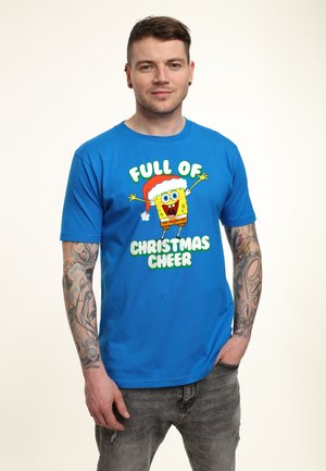 Blå kortærmet T-shirt med et grafisk motiv af en tegneseriefigur iført en julesok, med teksten "FULDT AF JULENISSE" i grønt.