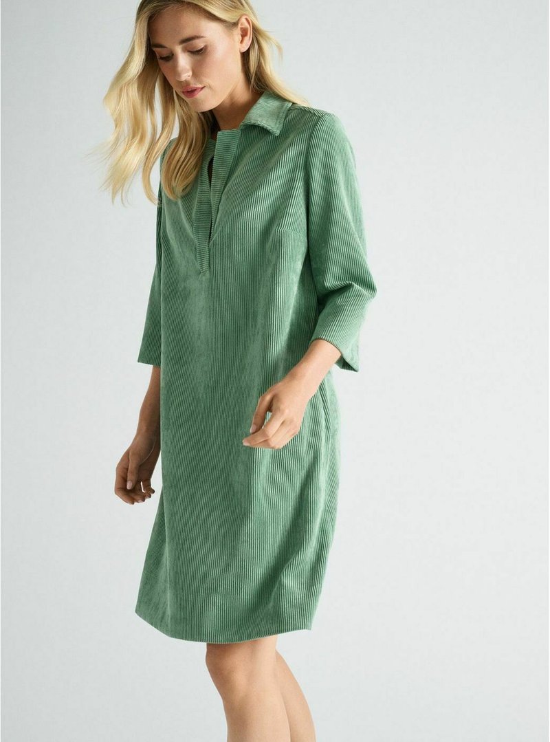 Groene corduroy jurk met een kraaghalslijn, driekwart mouwen, een voorpaspel en verticale ribbeltextuur.