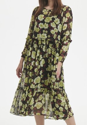 Robe midi florale avec une base noire, ornée de grandes fleurs vertes et rouges, en tissu transparent, à manches longues et avec une jupe à volants.