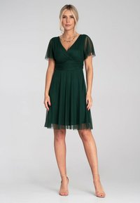 Grünes Kleid mit kurzen, transparenten Ärmeln, einem Wickel-V-Ausschnitt und einem fließenden A-Linien-Rock. Weicher Stoff mit einem leichten, strukturierten Aussehen.