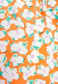 Tecido floral em laranja com padrões de pensões brancos e verdes, com realces roxos. Textura suave e contraste de cores vibrantes.